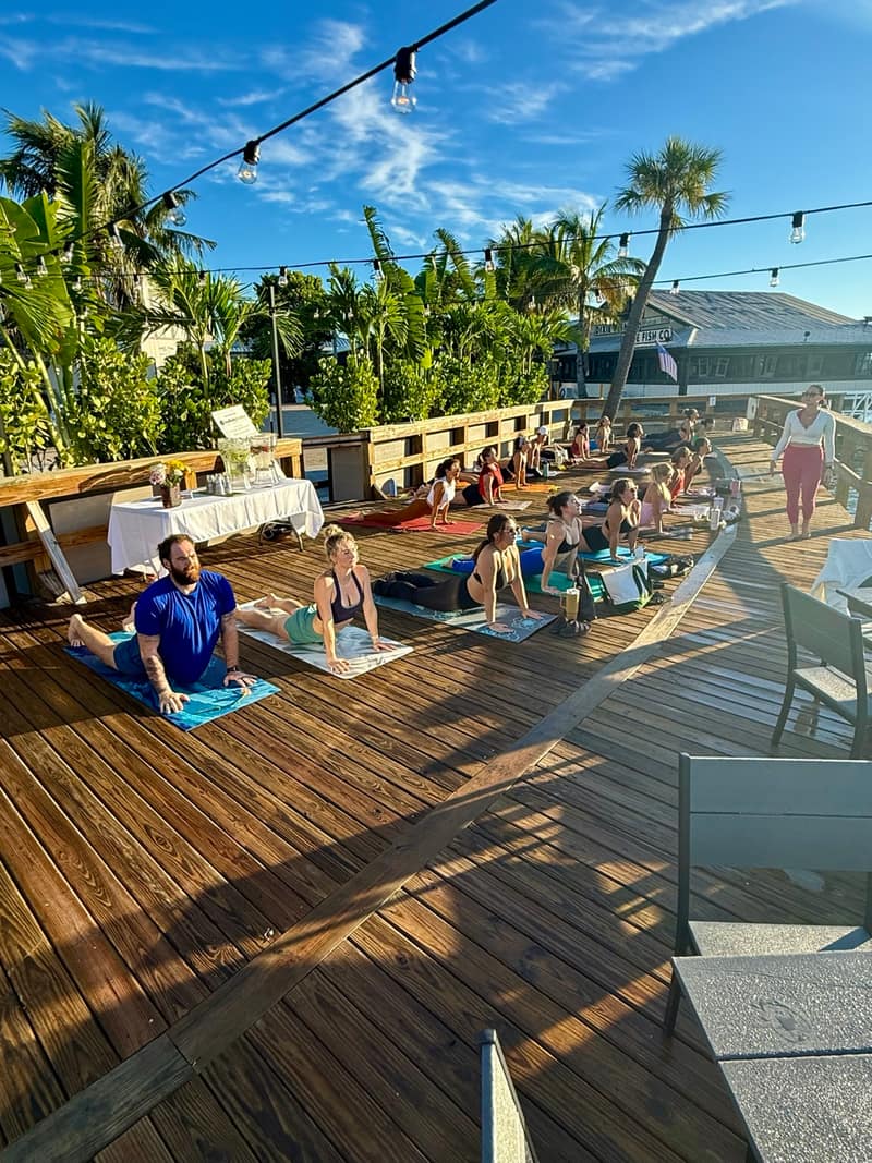 A full row of mats on the deck under string lights and palms